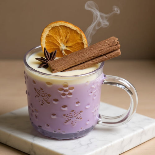 Hot beverage in a decorative mug with an orange slice, cinnamon stick, and star anise on a marble surface.