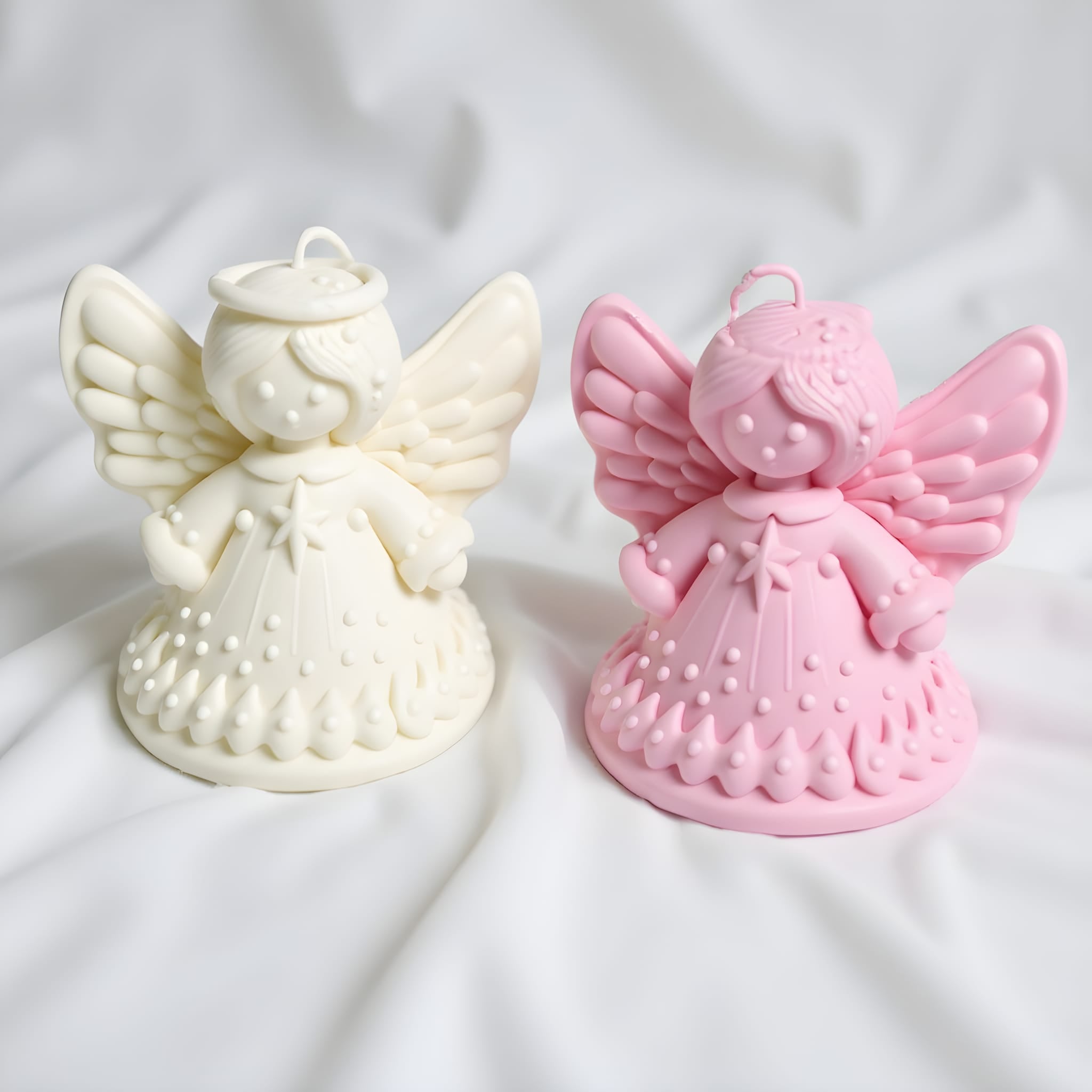 one angel-shaped candles, one white and one pink, on a white background.