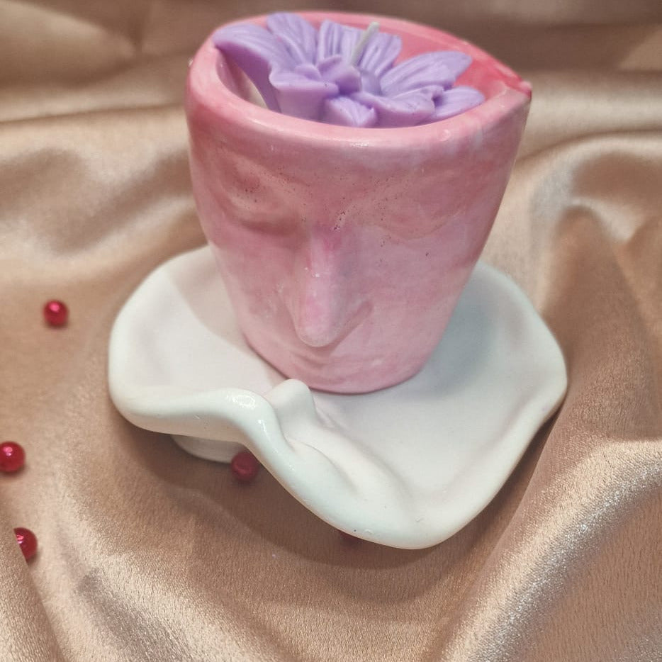 Pink and purple candle in a decorative holder on a beige fabric background