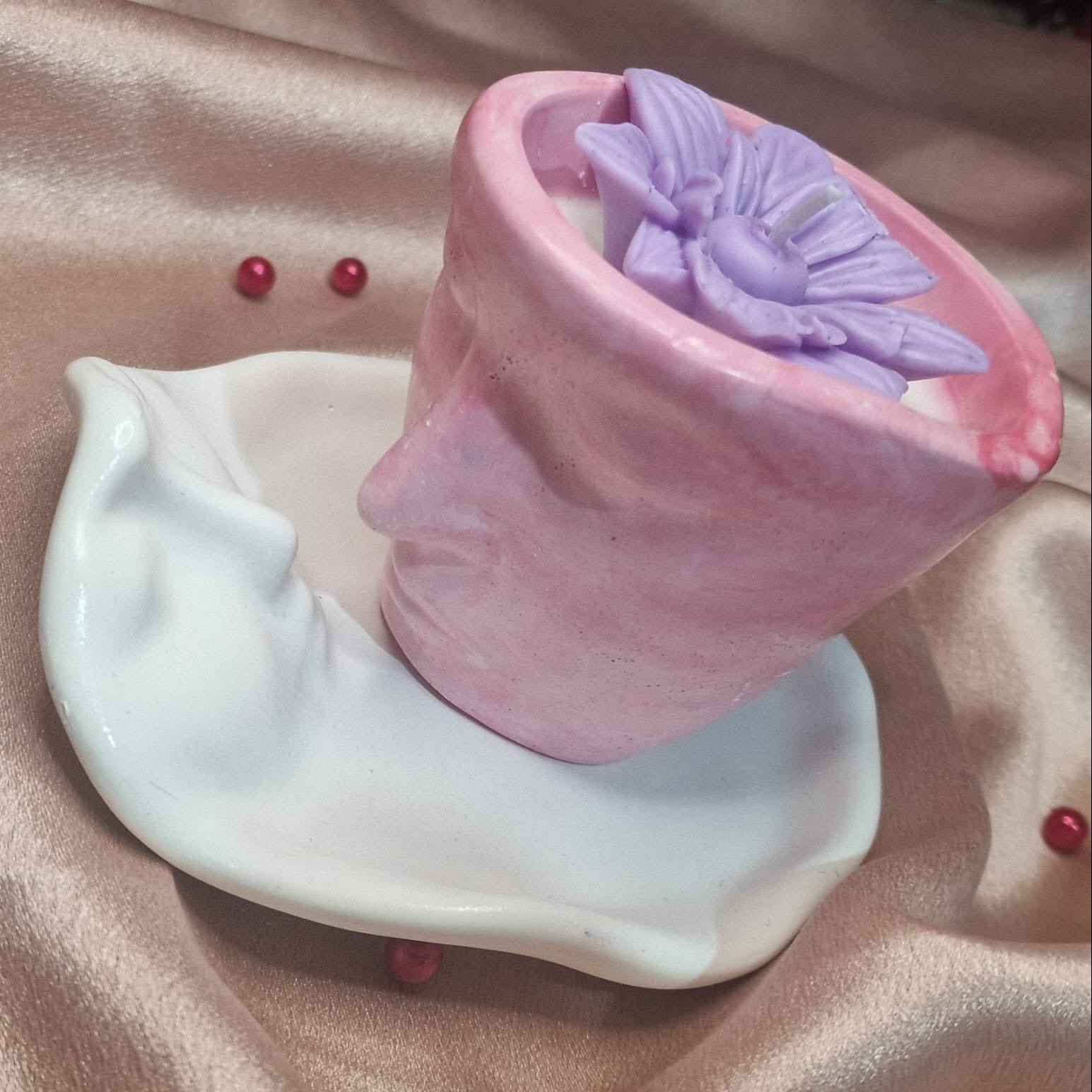 Pink and white ceramic items on a beige fabric background with red berries.