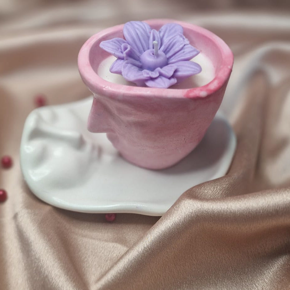 Pink flowerpot with a purple flower on a beige fabric background