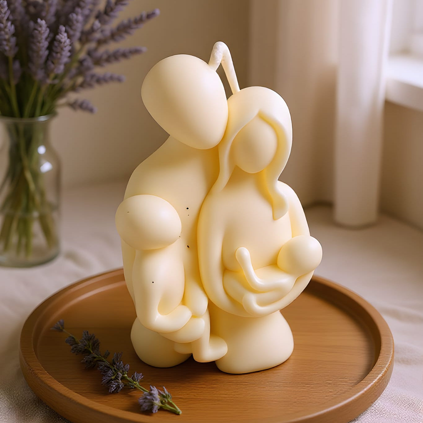 Candle sculpture of a couple on a wooden tray with lavender in the background