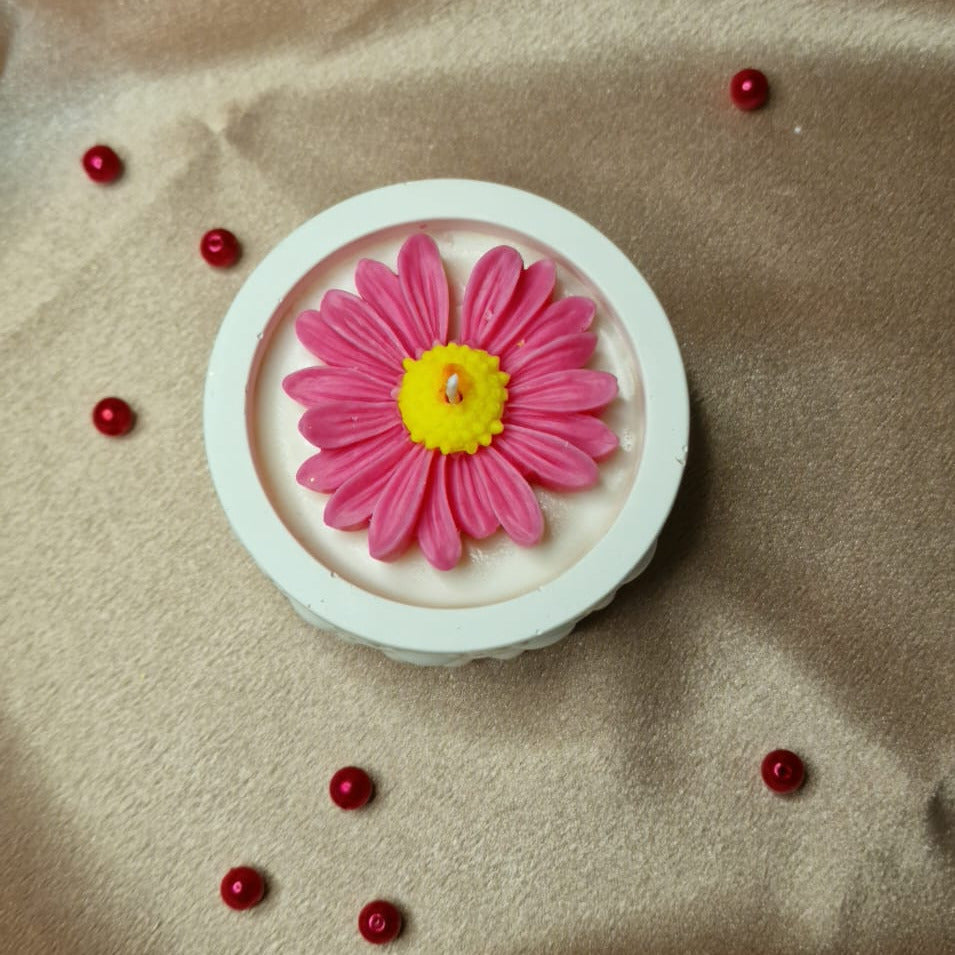 Pink flower-shaped object on a beige fabric background with small red beads.