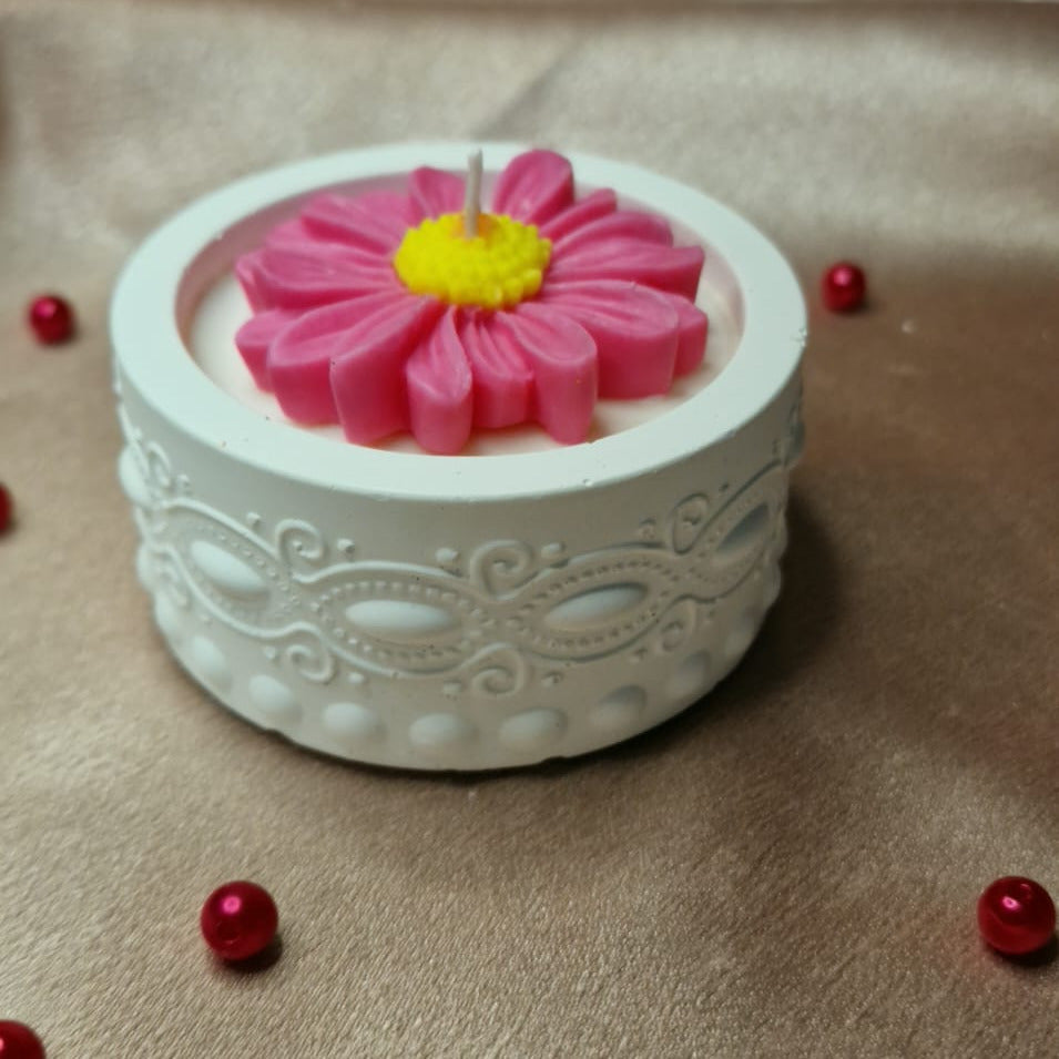 Decorative white container with a pink flower on a beige fabric background