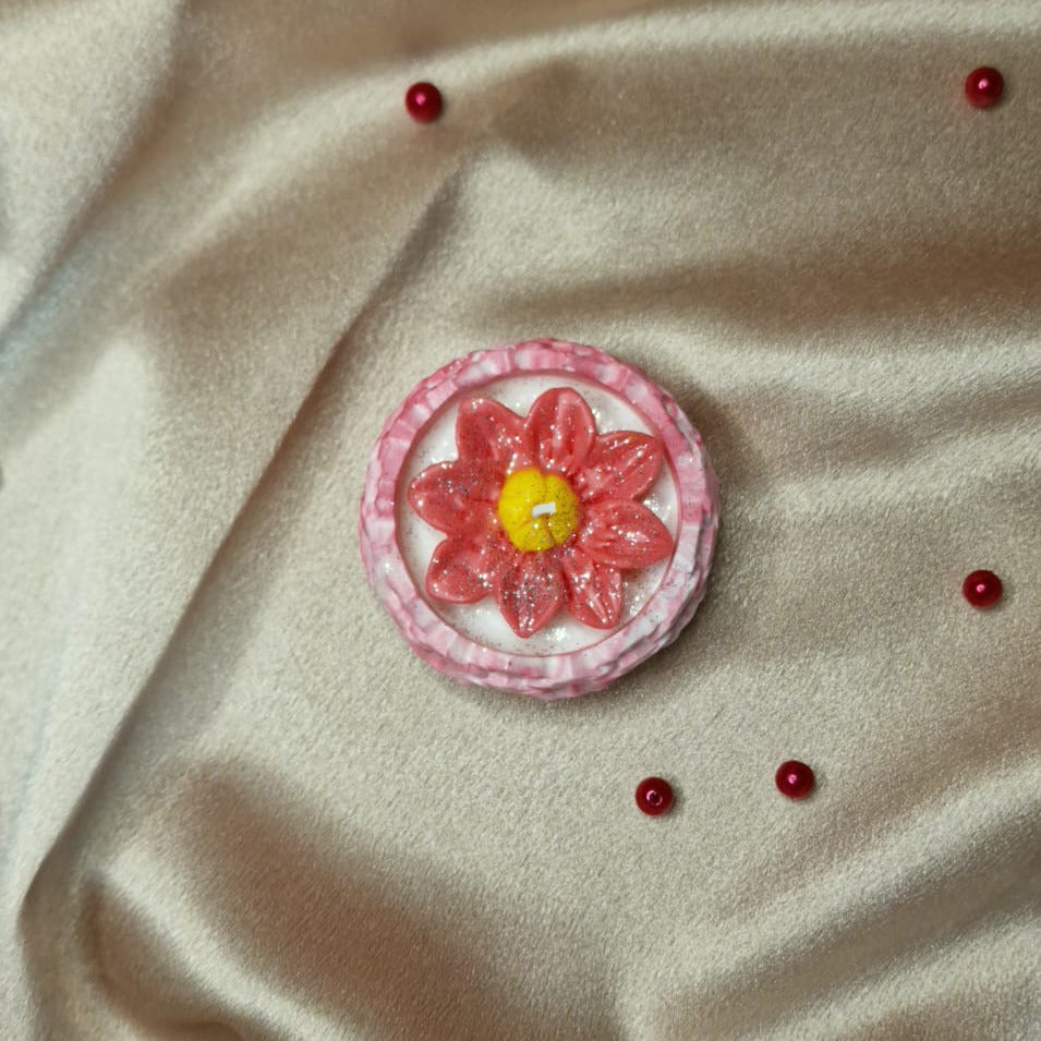 Pink flower brooch with a yellow center on beige fabric